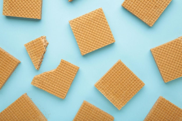 Quadratische Schokoladen-Waferkekse auf blauem Hintergrund. Ansicht von oben.