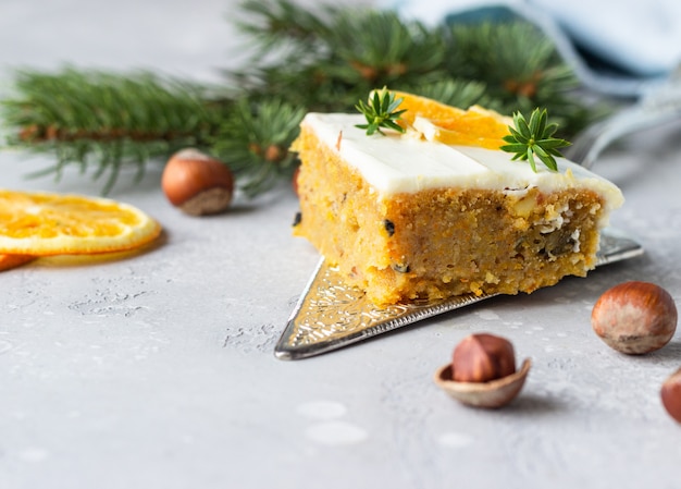 Quadratische Stücke des rohen gewürzten Karottenkuchens mit dem Orangen-, Nuss- und Frischkäsezuckerguss.