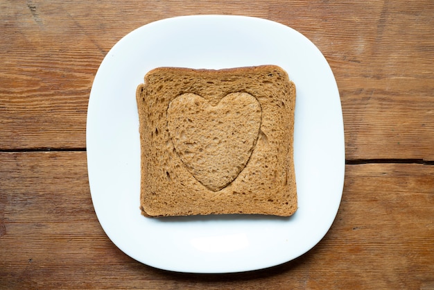 Quadratischer gegrillter Toast mit Herzsymbol-Prägung auf weißem Teller