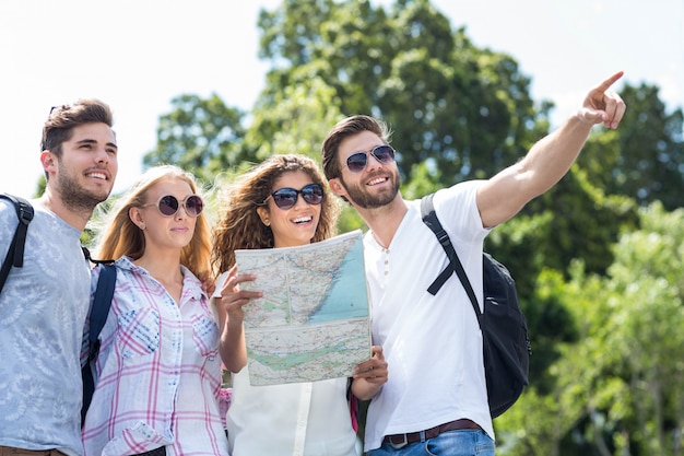 Quadril amigos segurando o mapa e apontando ao ar livre