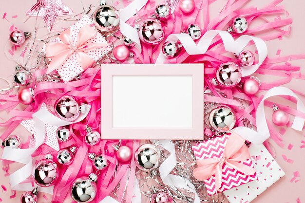 Quadro com bolas de Natal, presentes, fitas e decorações na cor rosa com espaço de cópia para o texto. Fundo de férias. Camada plana, vista superior