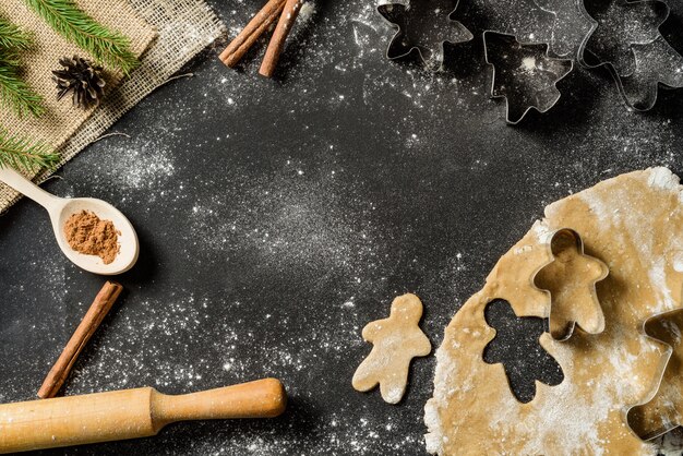 Quadro de comida de natal com biscoitos de gengibre, bakeware em fundo preto com espaço de cópia.