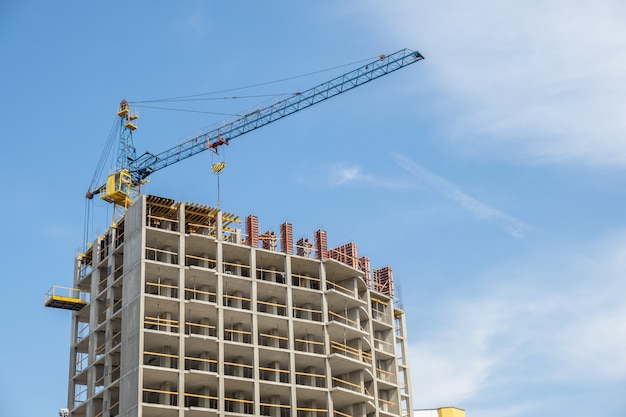 Quadro de concreto do prédio alto em construção e guindaste de torre em uma cidade.