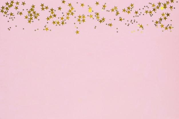 Quadro de estrelas douradas glitter confetes em fundo rosa.