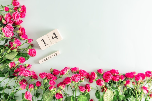 Quadro de flor festiva de mini rosas cor de rosa e um calendário de madeira com a data de 14 de fevereiro o conceito de cartão postal do dia dos namorados um espaço de cópia