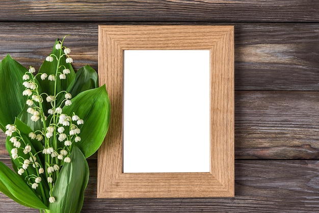 Quadro de foto em branco com flores de lírio do vale de primavera bouquet em casamento de fundo de madeira rústico