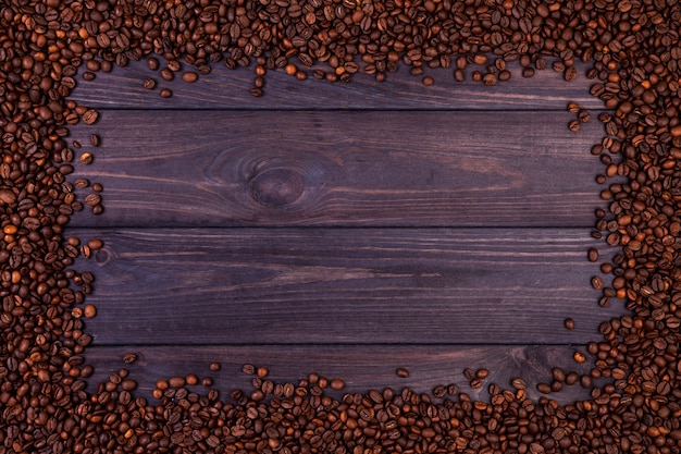 Quadro de grãos de café no fundo escuro de madeira. vista superior com espaço de cópia