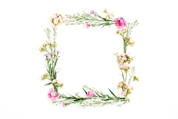 Quadro de grinalda feito de flores silvestres rosa e bege, folhas verdes, galhos em branco