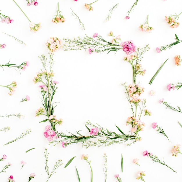Quadro de grinalda feito de flores silvestres rosa e bege, folhas verdes, galhos em branco
