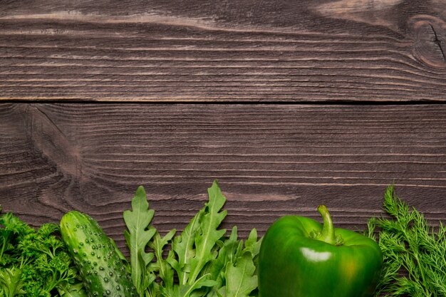 Foto quadro de legumes, vegetais verdes e folhas na mesa de madeira, vista superior