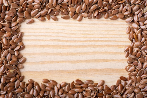 Quadro de sementes de linho sobre fundo de madeira claro Quadro natural de grãos de linho na mesa