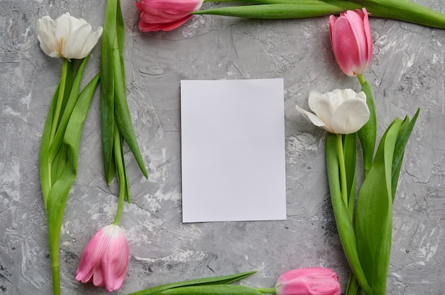 Quadro de tulipas e cartão em fundo cinza do grunge. Flores de primavera desabrochando, decoração floral fresca, frescor verde, presente romântico