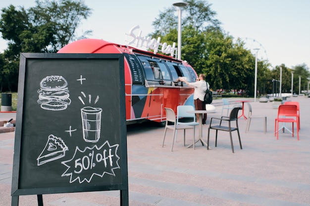 Quadro-negro com foto de lanches e bebidas anunciando desconto