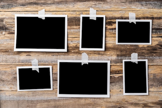 Quadros de fotos em branco de papel pendurados na parede de madeira