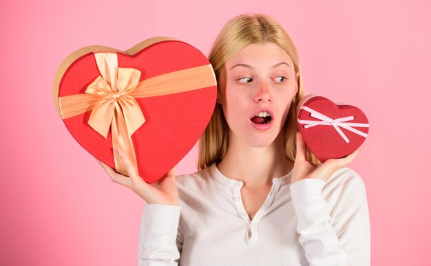 Qual ela prefere Garota decide qual presente ela gosta mais Grande surpresa e pequeno presente Faça a escolha Presente romântico para ela O tamanho realmente importa Mulher segura caixas de presente em forma de coração grandes e pequenas