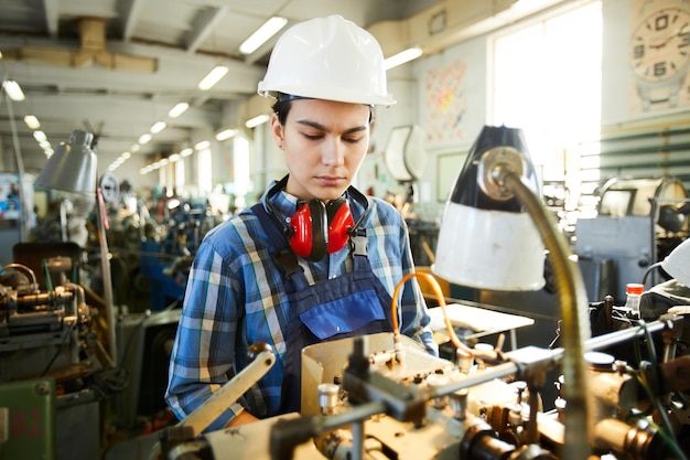 Qualifizierte Mitarbeiterin, die an einer Drehmaschine arbeitet