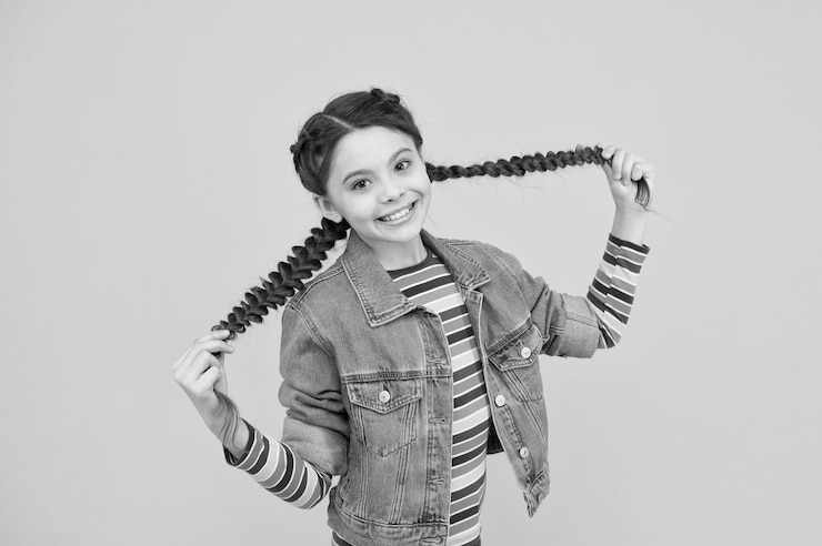 Foto quando meu cabelo é comprido eu vou ao cabeleireiro criança feliz segura cabelo comprido garota pequena em tranças penteado longo na moda estimulante de crescimento de cabelo comprido extensões de cabelo naturais cuidados com o cabelo de salão