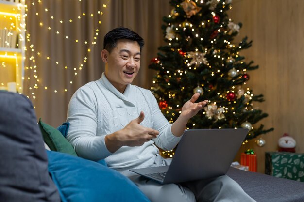 Quarantäne für den Urlaub junger gutaussehender asiatischer Mann, der an Neujahr in der Nähe allein zu Hause auf dem Sofa sitzt