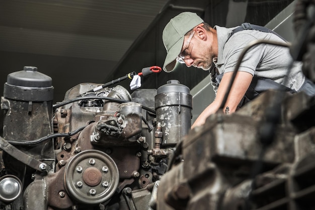 Foto quarenta anos velhos motores a diesel caucasianos técnico automotivo restaurando motor de caminhão tema da indústria automotiva