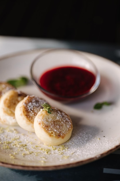 Quark Krapfen dekoriert Puderzucker in Teller Käsekuchen frische Marmelade Sauerrahm und Minze