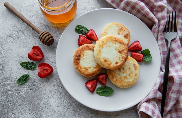 Quark-Pfannkuchen-Ricotta-Krapfen auf Keramikplatte mit frischen Erdbeeren