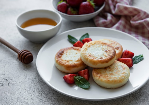 Quark-Pfannkuchen-Ricotta-Krapfen auf Keramikplatte mit frischen Erdbeeren