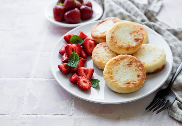 Quark-Pfannkuchen-Ricotta-Krapfen auf Keramikplatte mit frischen Erdbeeren