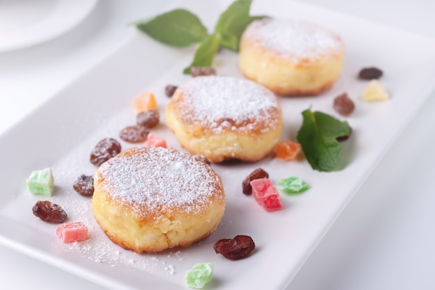 Quarkpfannkuchen mit Rosinen und kandierten Früchten auf einer weißen Plattenoberansicht