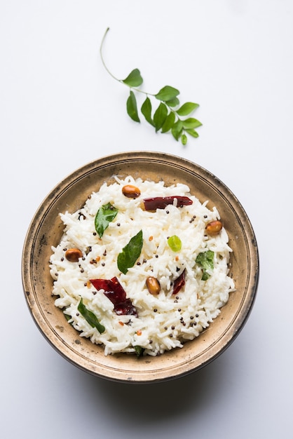 Quarkreis oder Dahi Bhat ODER Chawal mit Curryblatt, Erdnüssen und Chili - Serviert in einer Schüssel über stimmungsvollem Hintergrund. Selektiver Fokus