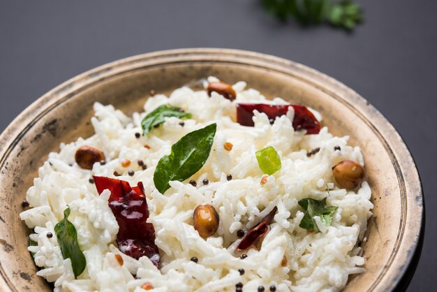 Quarkreis oder Dahi Bhat ODER Chawal mit Curryblatt, Erdnüssen und Chili - Serviert in einer Schüssel über stimmungsvollem Hintergrund. Selektiver Fokus