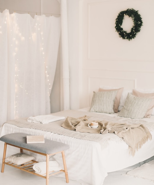 Quarto aconchegante e leve decorado para o Natal e Ano Novo com uma coroa de flores na parede