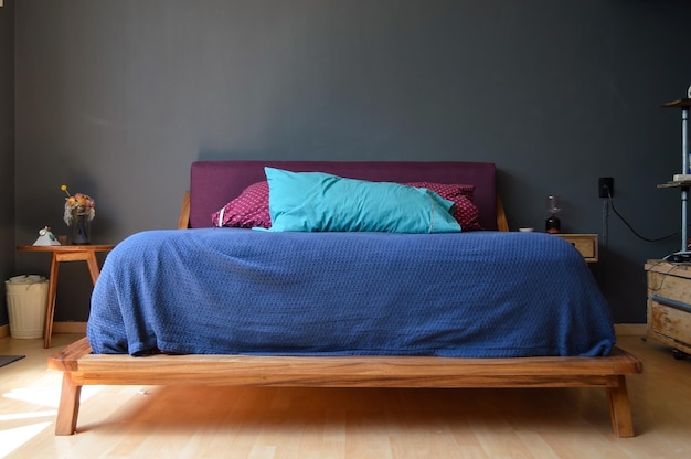 Quarto base da cama com tapete no chão vaso de barro ao fundo aparador de madeira e espelho