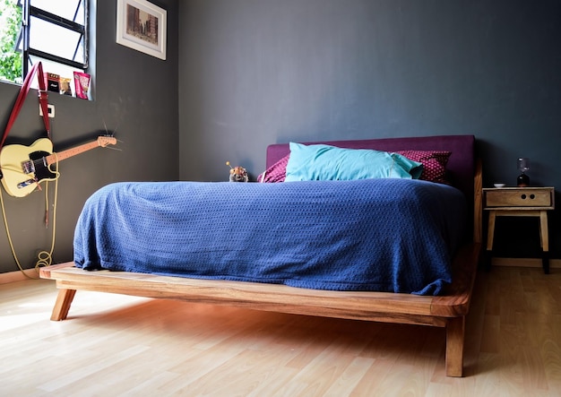 Quarto base da cama com tapete no chão vaso de barro ao fundo aparador de madeira e espelho