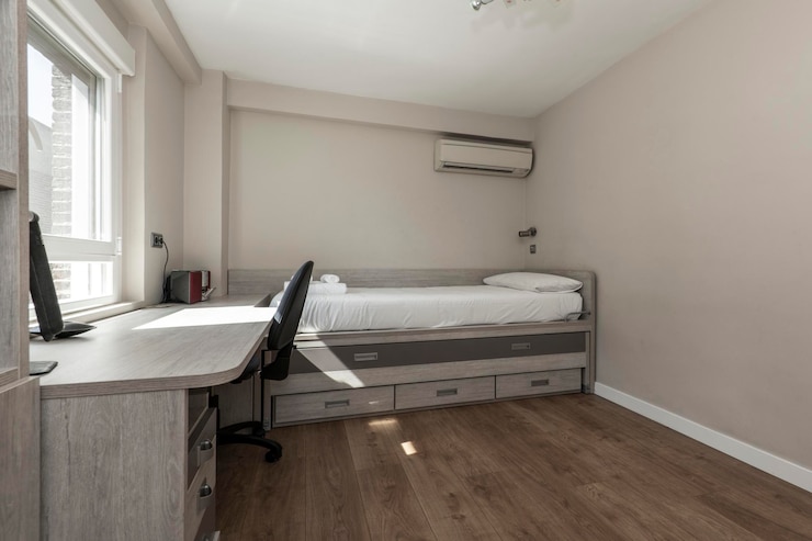 Foto quarto com bicama juvenil com gavetas e escrivaninha combinando com cadeira giratória com piso de madeira escura