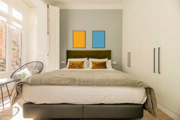 Foto quarto com cabeceira de cama de casal estofada em tecido veludo verde combinando com almofadas e almofadas roupeiros embutidos com portas brancas varanda com janelas e persianas de madeira branca