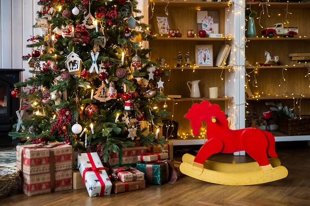 Quarto com interior de natal, árvore de natal decorada com guirlanda e cadeira de balanço vermelha