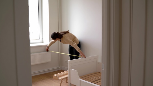 Quarto de criança da renovação da jovem mulher na casa nova. Estante de madeira Berçário neutro