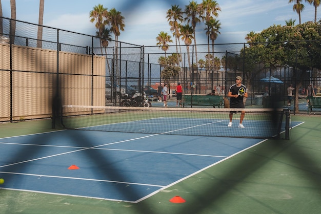 Foto quarto de tênis ao ar livre com jogador servindo em los angeles