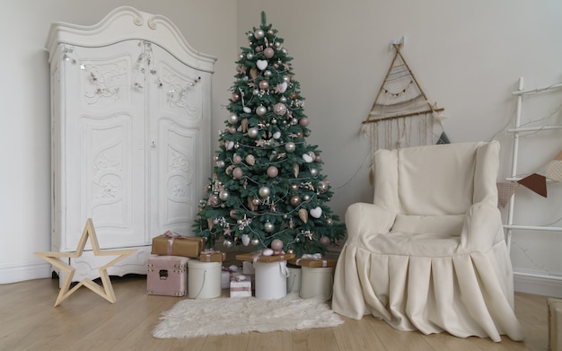 Quarto decorado para as férias de natal - presentes sob a árvore de natal, guarda-roupa branca e poltrona coberta