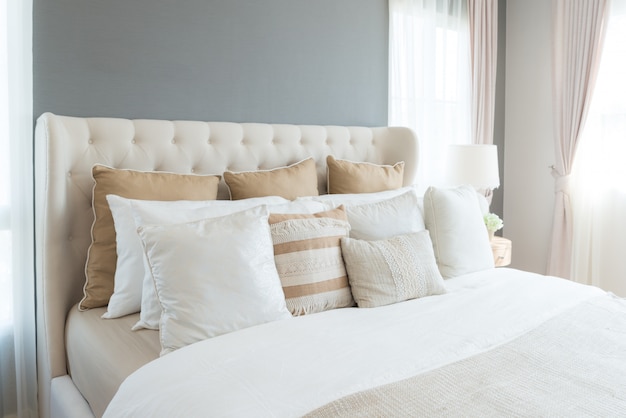Quarto em cores suaves de luz. grande cama de casal confortável no elegante quarto clássico em casa.