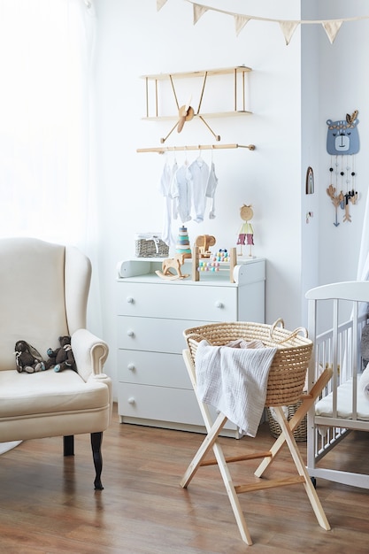 Quarto infantil com interior branco de estilo escandinavo, quarto, creche. Berço com â € ¢ dossel. Prateleiras e brinquedos em madeira. Berço de vime com pernas