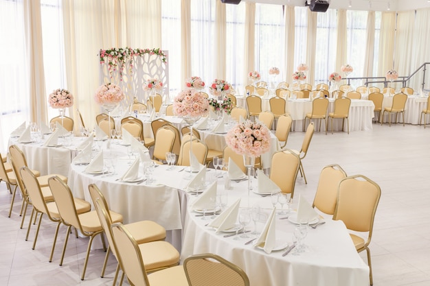 Quarto lindamente decorado com mesas cobertas com flores no restaurante