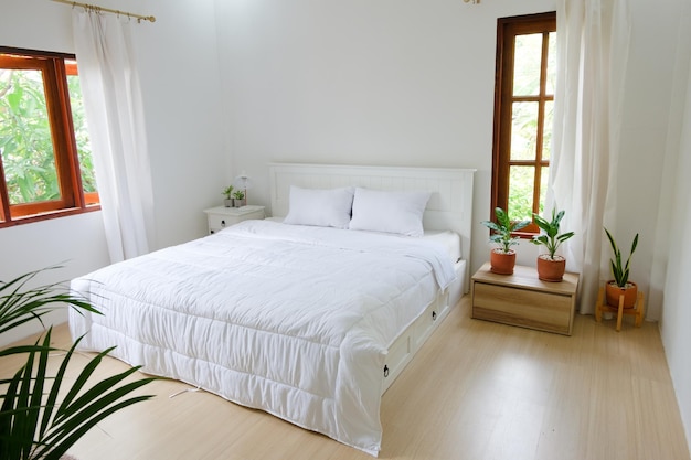 Quarto mínimo com cama branca de piso de madeira e plantas