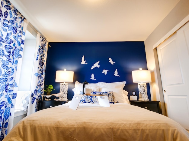 Foto quarto principal moderno com parede azul e lençóis brancos.