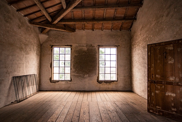 Quarto vazio em uma casa abandonada com janela e piso de madeira