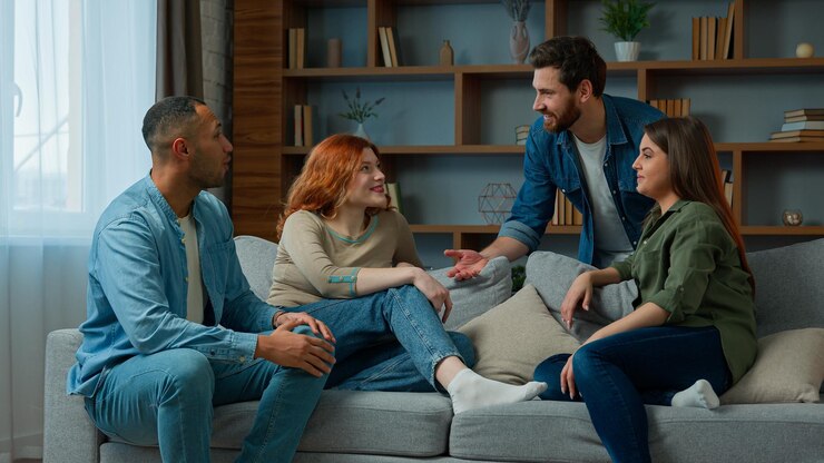 Foto quatro amigos étnicos colegas companheiros sentam-se no sofá de casa conversando discutem planos conversando amigavelmente