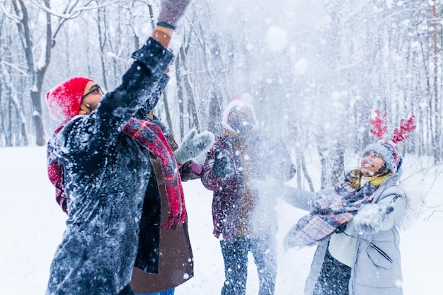 Quatro amigos felizes estão se divertindo e jogando neve