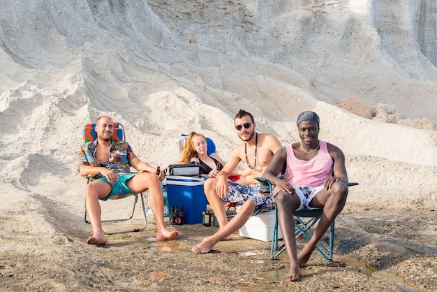 Quatro amigos sentados na praia fazendo um piquenique