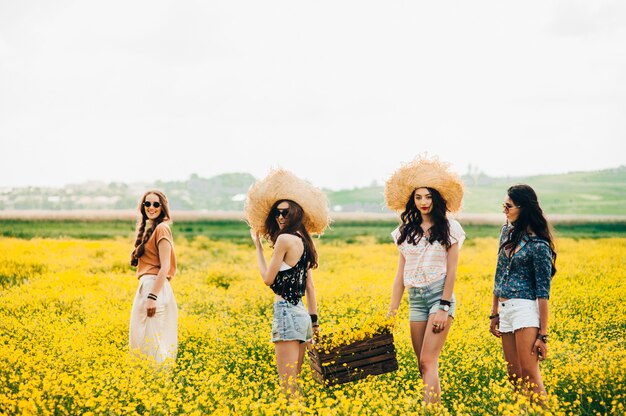 quatro bela garota hippie em um campo de flores amarelas