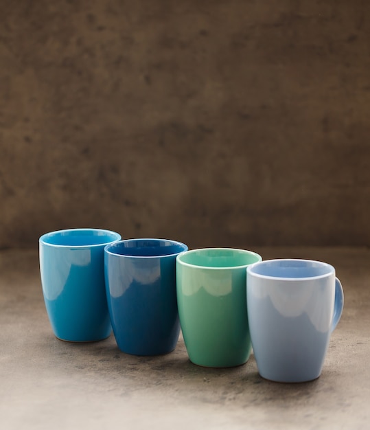 Foto quatro canecas de chá de cores diferentes em um fundo cinza